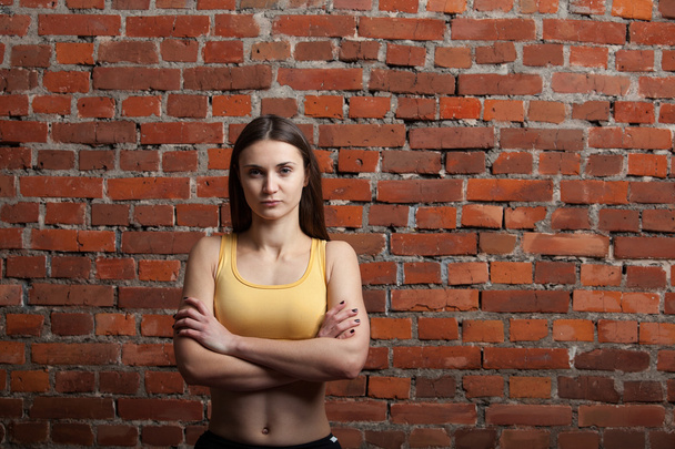mujer atlética severa sobre fondo de pared de ladrillo
 - Foto, Imagen