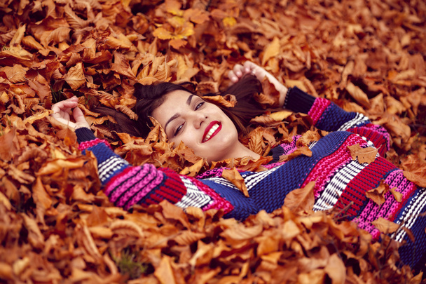 herfst vrouw liegen over bladeren en lachende, bovenaan weergave - Foto, afbeelding