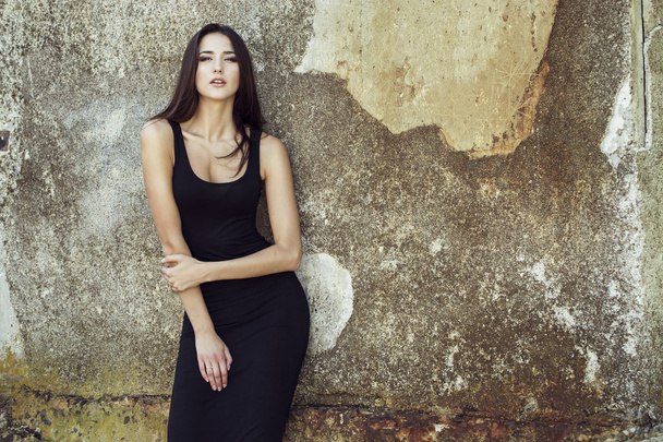 Fashion portrait of young beautiful brunette girl in sexy black dresss.  Outdoor shot.  Urban style - Photo, Image