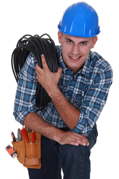 Tradesman carrying a cable coiled around his shoulder - Foto, imagen