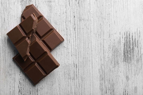 Pedaços de chocolate preto na cor de fundo de madeira
 - Foto, Imagem