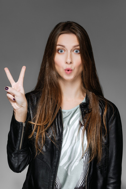 young lady in leather jacket shows two fingers and says two - Foto, Imagen