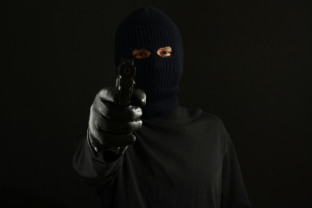 Bandit in black mask with gun isolated on black - Foto, Bild