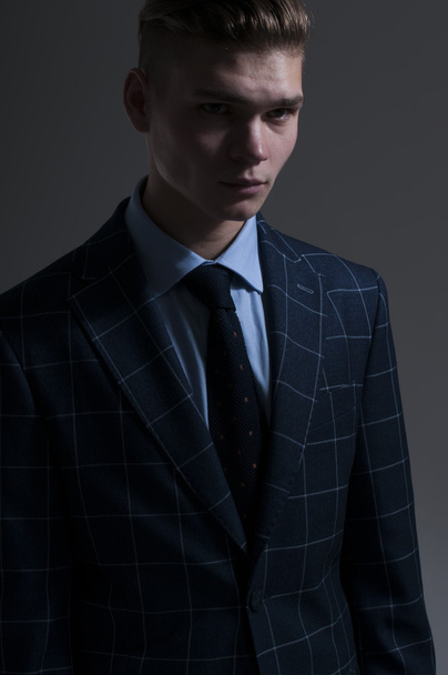 Seductive young man in a suit posing on gray background - Valokuva, kuva