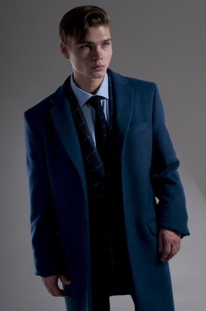 Portrait of attractive man in blue coat over gray background. - Foto, afbeelding