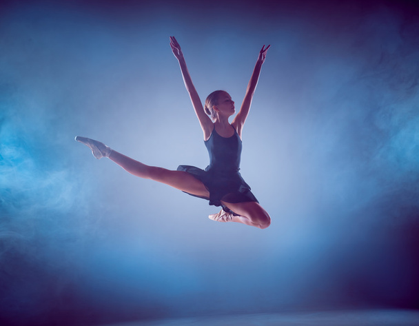 The silhouette of young ballet dancer jumping on a blue background. - Valokuva, kuva