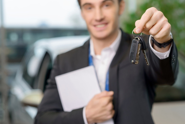 Young salesman is upholding the car keys. - Фото, зображення