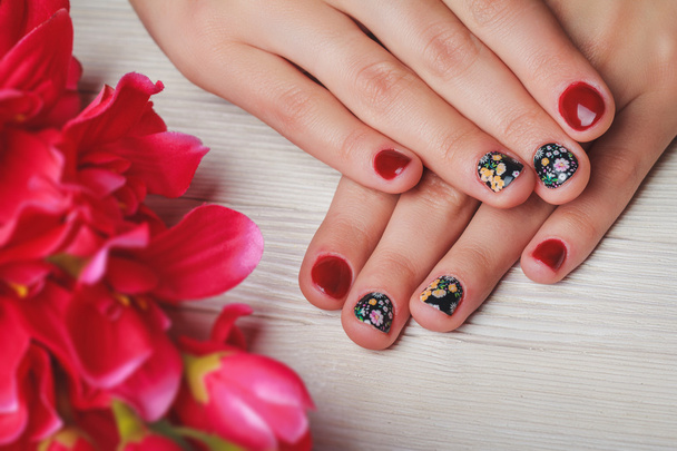 Red nail art with printed flowers on wooden background - Zdjęcie, obraz