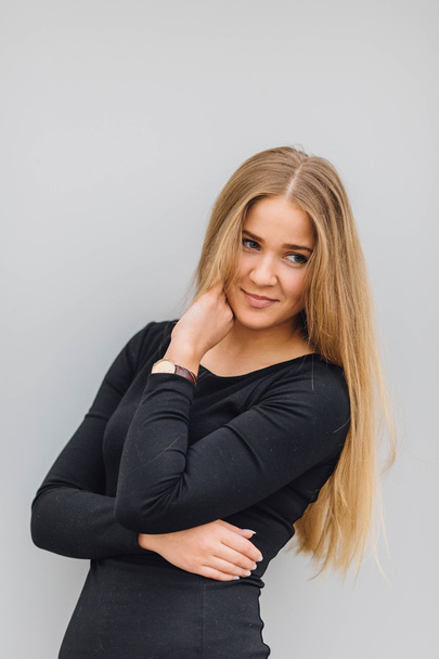 Blonde young woman standing behind the wall and posing ti camera - Photo, image