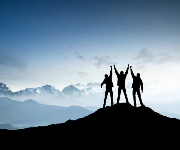 Silhouettes of team on mountain peak - Photo, Image