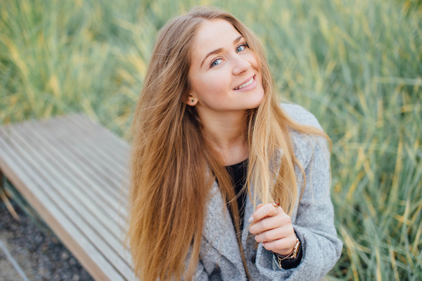 Blonde hair woman sitting on the bench and smile - Fotoğraf, Görsel