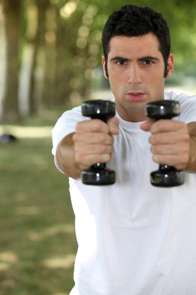 Man lifting weights in park - Photo, image