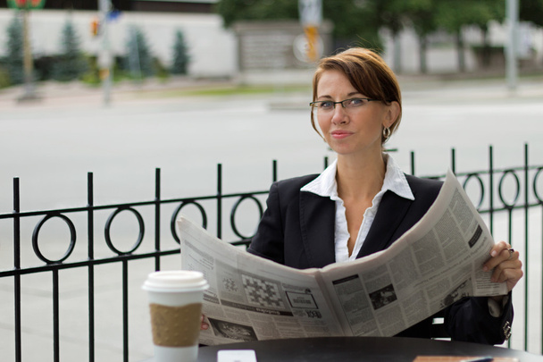 Деловая женщина читает газеты за чашкой кофе
 - Фото, изображение