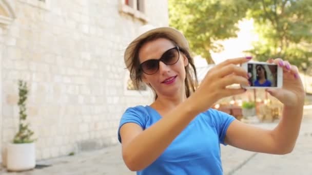 Fille dans le chapeau et les lunettes de soleil faisant selfie par le smartphone
 - Séquence, vidéo
