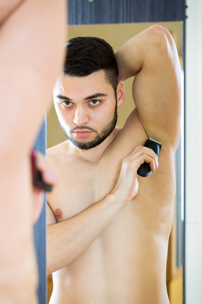 Young guy shaving armpit - Foto, afbeelding