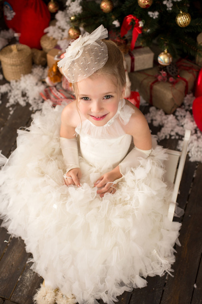 Cute Young beautiful girl in white Christmas dress is sitting on - Foto, afbeelding