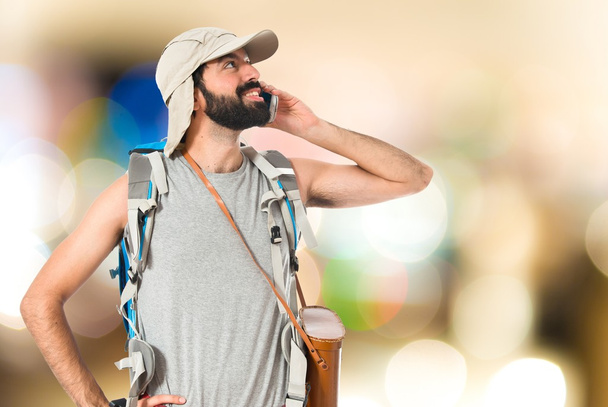 Backpacker talking to mobile over white background - Foto, Imagen