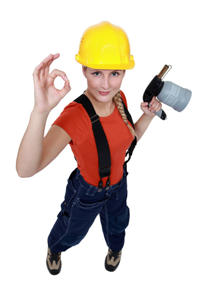 Tradeswoman holding a blowtorch and giving the a-ok sign - 写真・画像