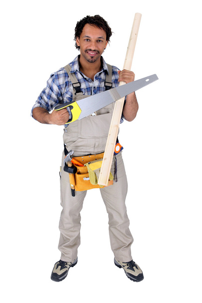 werknemer holding een zaag en een stuk hout - Foto, afbeelding