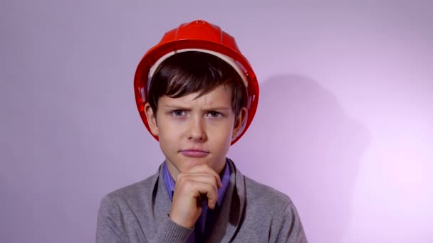 Teen chlapec tvůrce v oranžovou helmu myslím, že problém studiový portrét - Záběry, video