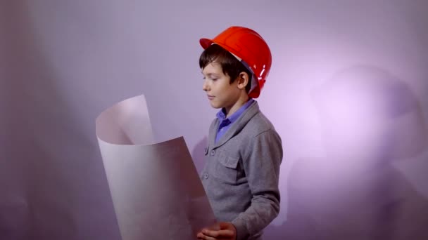 builder boy teen in helmet holding building plan documents - Filmati, video