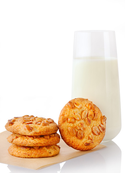Three homemade peanut butter cookies on baking paper, single cookie and glass of milk - Zdjęcie, obraz