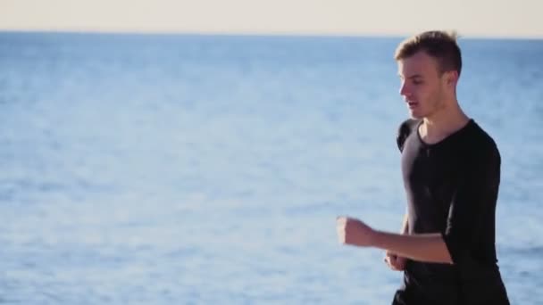 młody człowiek działa na plaży zwolnionym tempie - Materiał filmowy, wideo