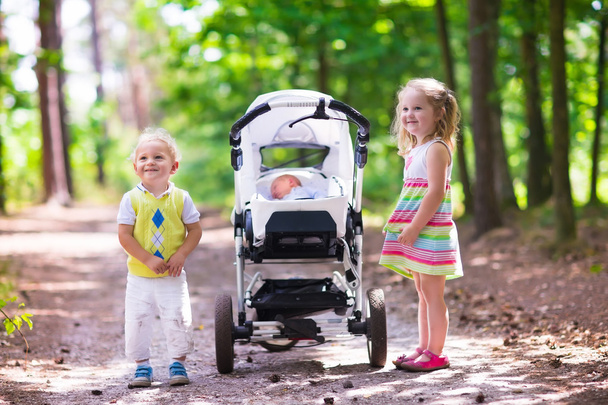 Kinderen duwen wandelwagen met pasgeboren baby - Foto, afbeelding