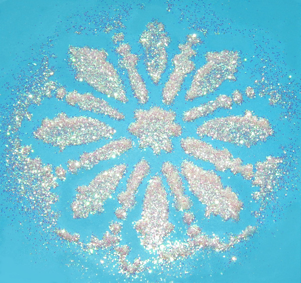 verschwommener Hintergrund mit Schneeflocke aus weißem Glitzer funkelt auf blauem Grund - Foto, Bild