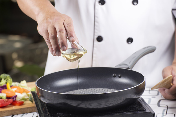 Chef pouring vegetable oil to the pan  - Photo, image