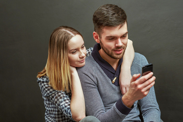 Young bearded man sitting next to his girlfriend while using sma - Фото, изображение