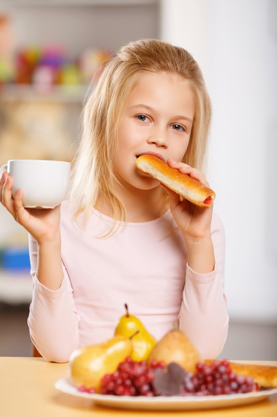 girl is drinking tea and eating pastry. - Φωτογραφία, εικόνα