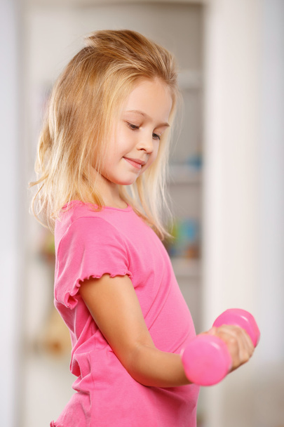 Little girl lifting a dumbbell. - Fotoğraf, Görsel