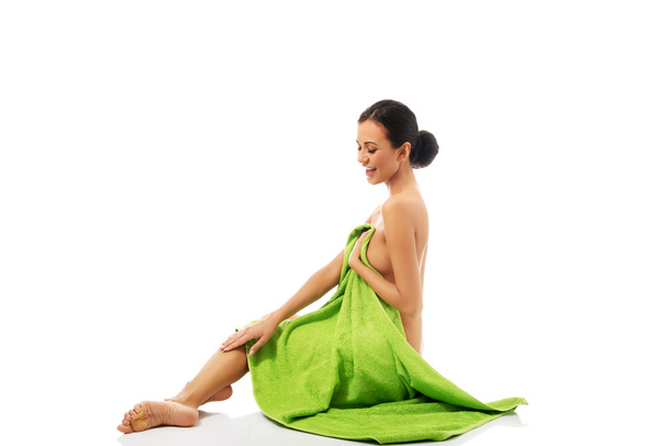 Laughing woman sitting wrapped in towel - Foto, Imagen