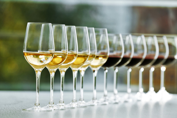 Gafas de vino con vino blanco y tinto sobre mesa de madera sobre fondo brillante
 - Foto, imagen
