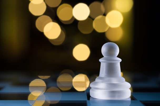 Faint Pawn On Blue Chessboard With Bokeh - 写真・画像