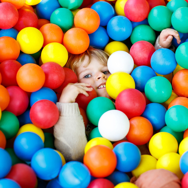 ребенок играет на ярких пластиковых мячах игровой площадке
 - Фото, изображение