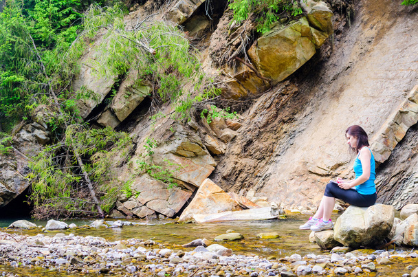 beautiful young girl sits on a rock in the river and draws from - Foto, Bild