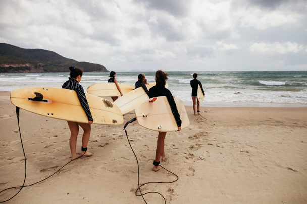 azonosítatlan nő szörfösök szörfözés táblák jön a tenger - Fotó, kép