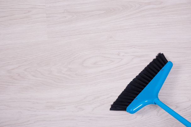 cleaning concept - close up of blue broom sweeping floor - Foto, imagen