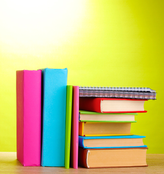 Books with stationery on wooden table on green background - Φωτογραφία, εικόνα