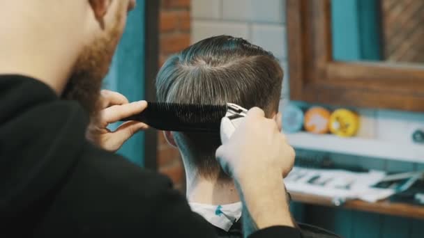 Κουρέας κόβει τα μαλλιά του πελάτη με κουρευτής ζώων - Πλάνα, βίντεο