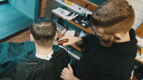 Fryzjer ścina włosy klienta maszynką - Materiał filmowy, wideo