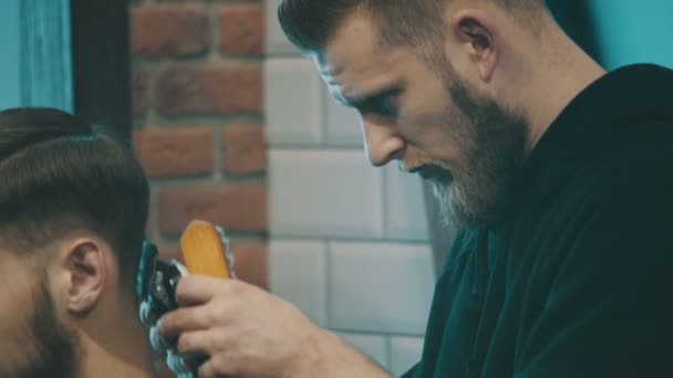 Fryzjer ścina włosy klienta maszynką - Materiał filmowy, wideo