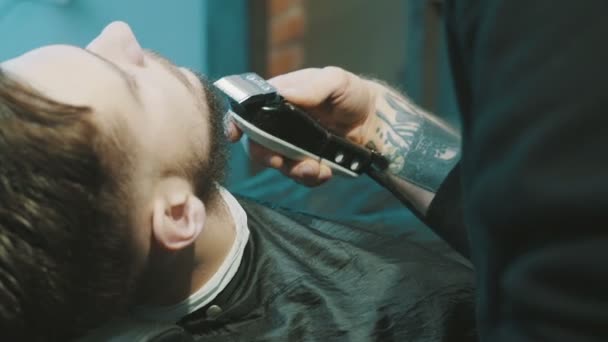 Peluquero afeitar la barba del cliente con clipper
 - Imágenes, Vídeo