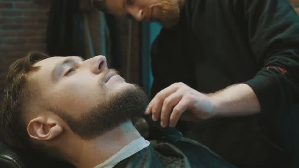 Peluquero afeitar la barba del cliente con clipper
 - Imágenes, Vídeo