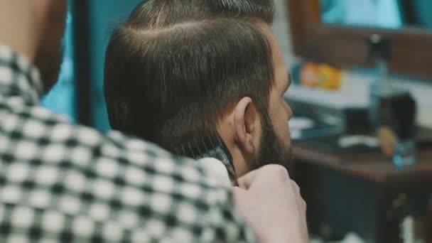 Peluquero corta el cabello del cliente con un cortador
 - Metraje, vídeo