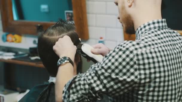 Peluquero corta el cabello del cliente con un cortador
 - Imágenes, Vídeo