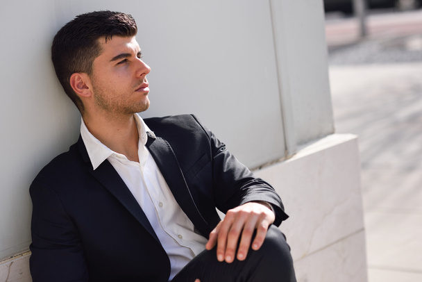 Young businessman near a office building wearing black suit - Foto, immagini