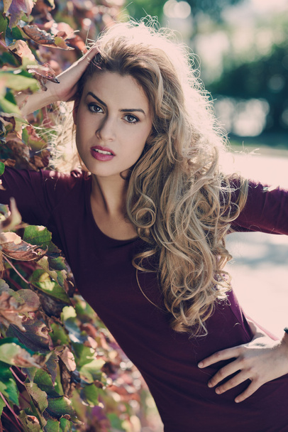 Young woman with long blond curly hair in urban background - Foto, Imagem